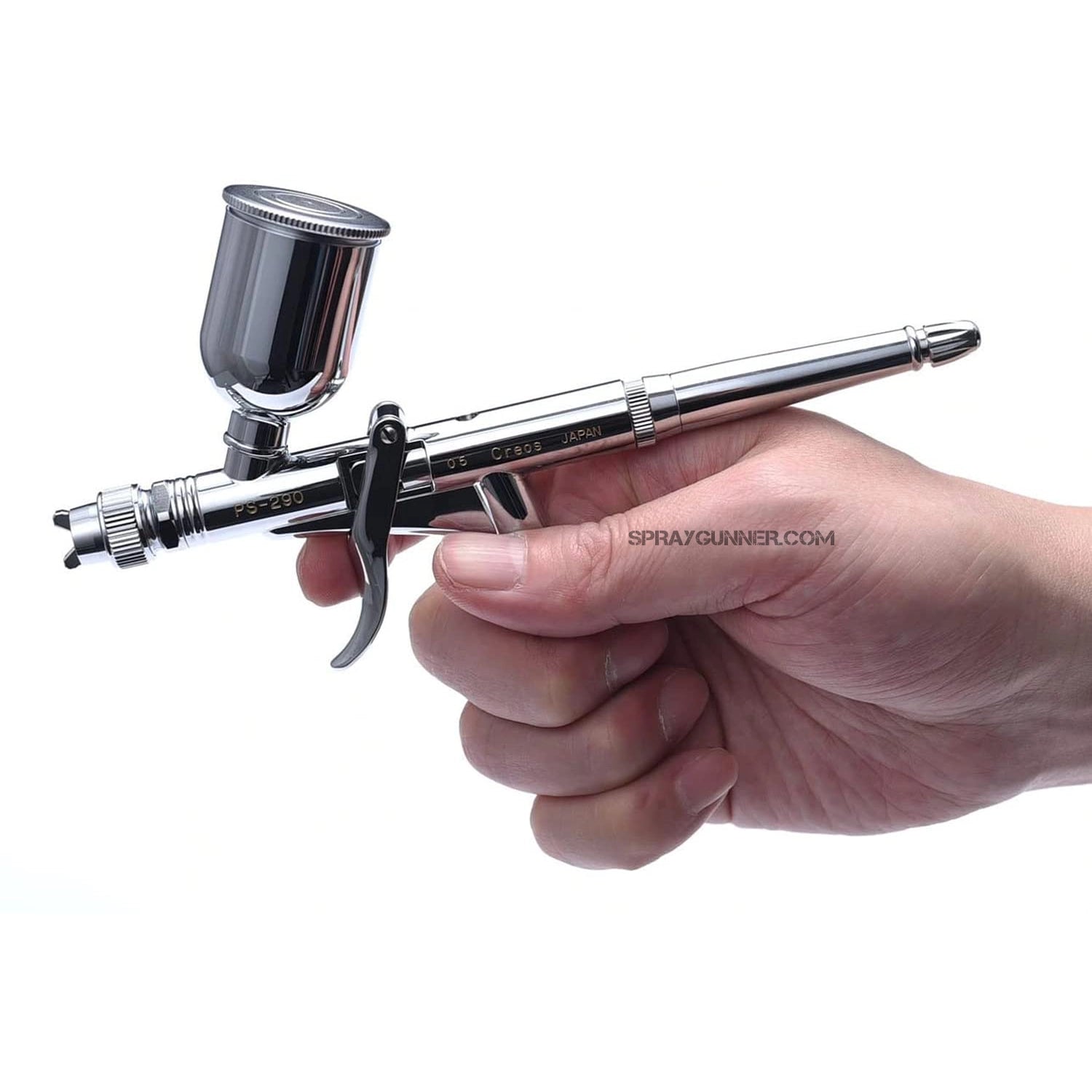 Hand holding the GSI Creos Mr. Hobby Procon Boy PS-290 airbrush, demonstrating its comfortable grip and professional-grade build.