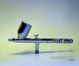 Shown in front of a branded packaging box is the IWATA VAULT KUSTOM CS Gravity Feed Dual Action Airbrush, which has a chrome body and nozzle.